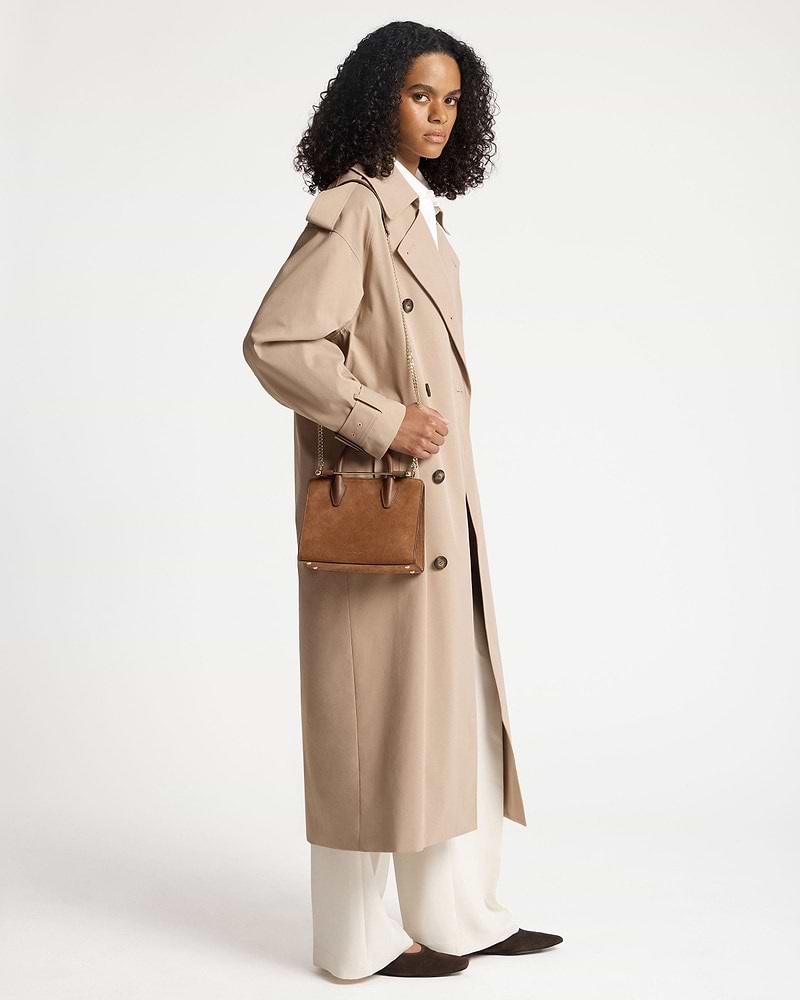 Model wearing tan suede mini tote with chain strap and top handles.