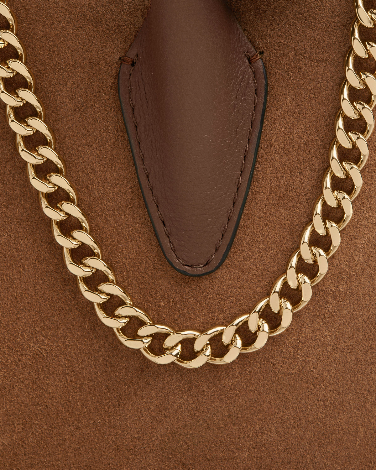 Tan suede mini tote with gold chain handle and stitched leather tab.