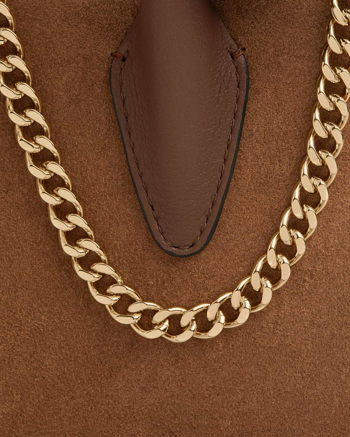 Tan suede mini tote with gold chain handle and stitched leather tab.