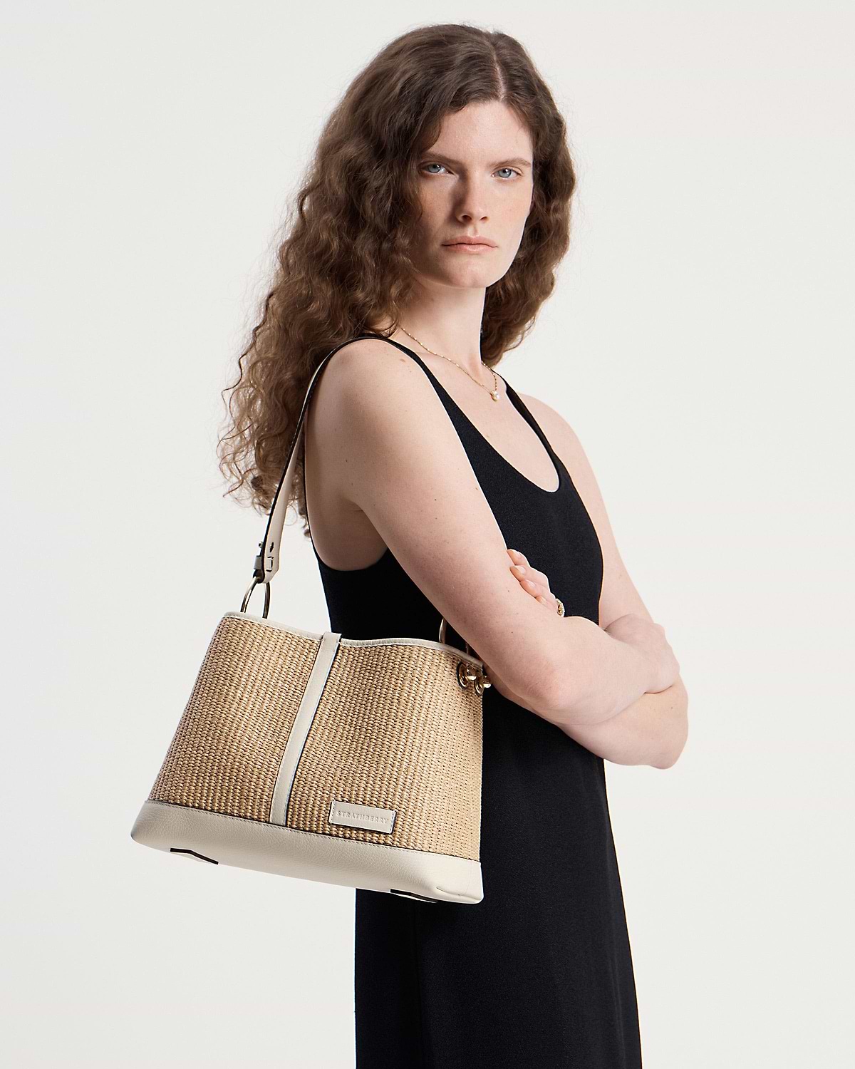 Model wearing Strathberry Lana Hobo bag in vanilla natural raffia on shoulder.