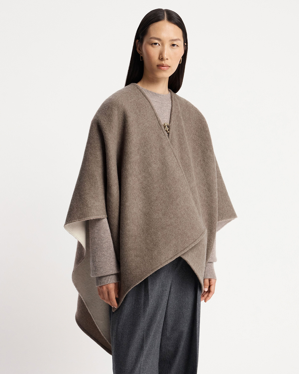 Model wearing taupe kite woven cape fastened with a gold clasp.