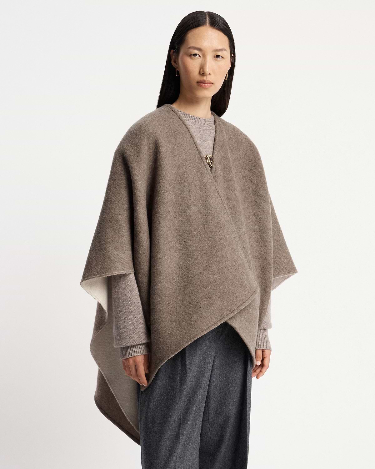 Model wearing taupe kite woven cape fastened with a gold clasp.