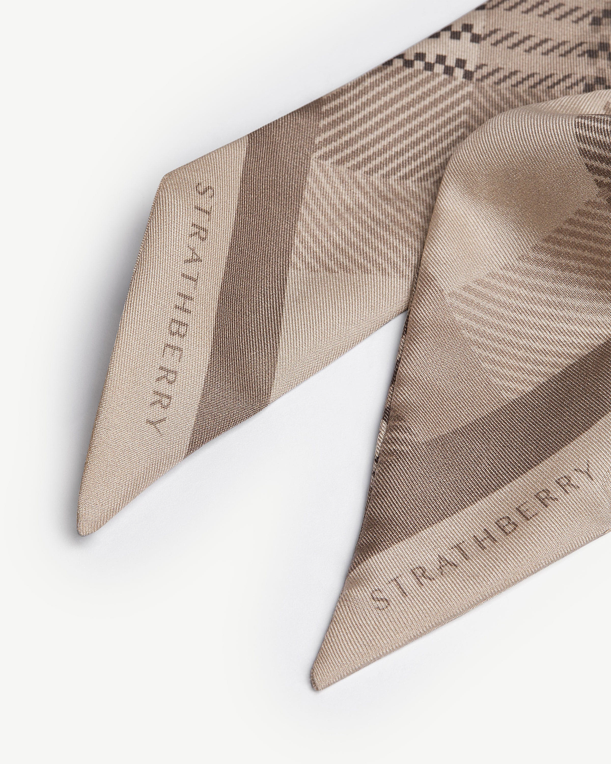Silk skinny scarf in oat tartan showing Strathberry wordmark, folded close-up.