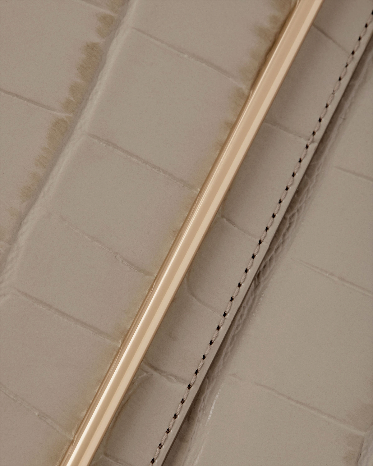 Croc-embossed leather strap with gold metal bar and stitched seam.