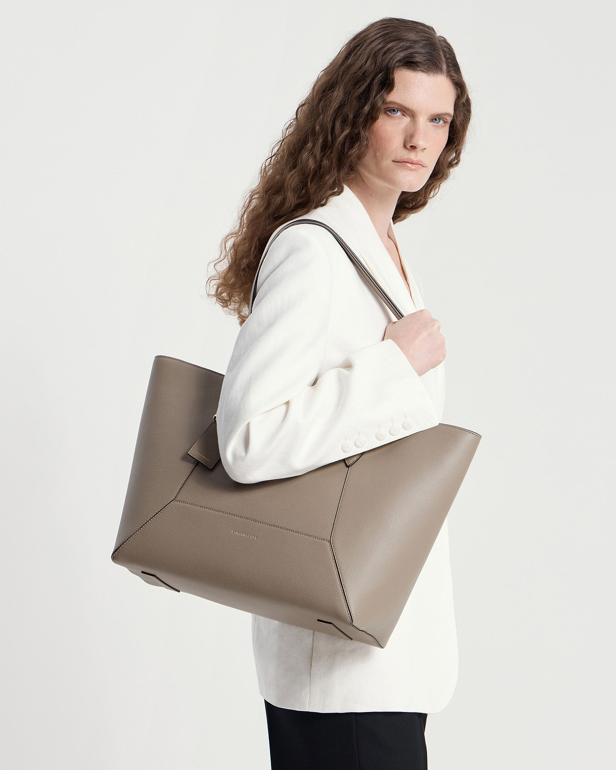 Model wearing a white blazer carrying a taupe Mosaic Cabas tote on her shoulder.