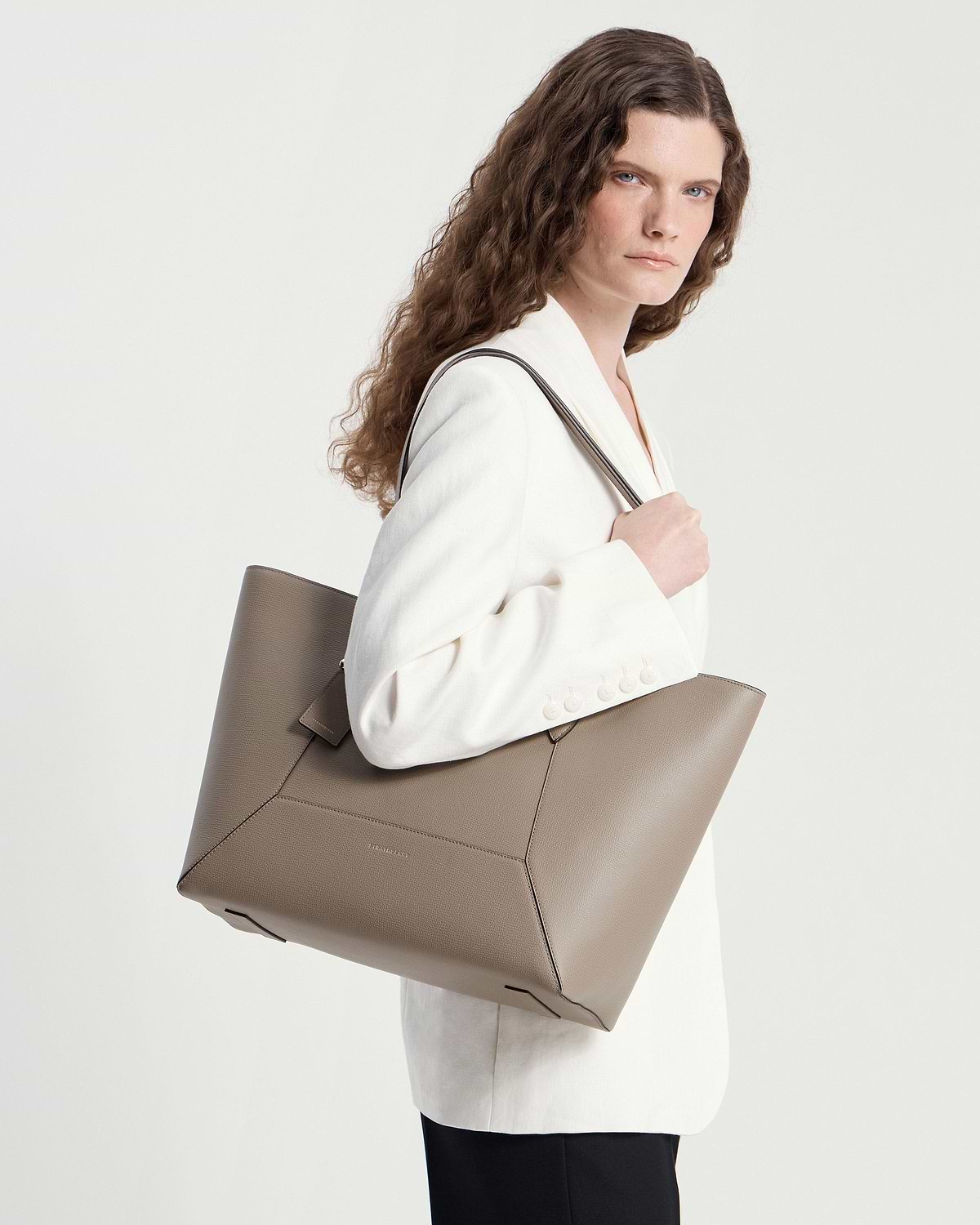 Model wearing a white blazer carrying a taupe Mosaic Cabas tote on her shoulder.