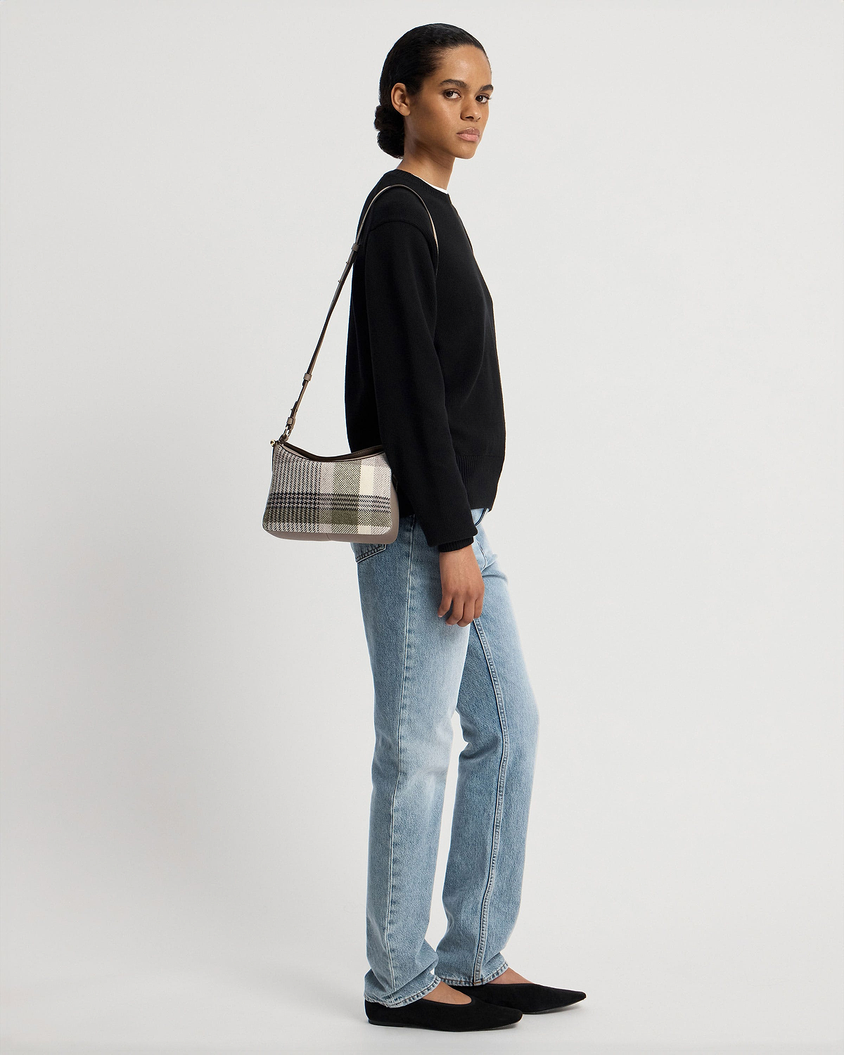 Model wearing checked tartan taupe shoulder bag with black jumper and jeans.