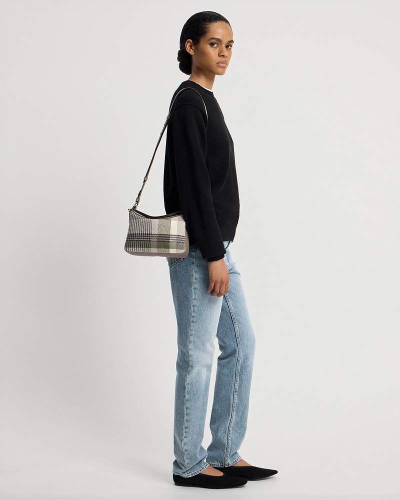 Model wearing checked tartan taupe shoulder bag with black jumper and jeans.