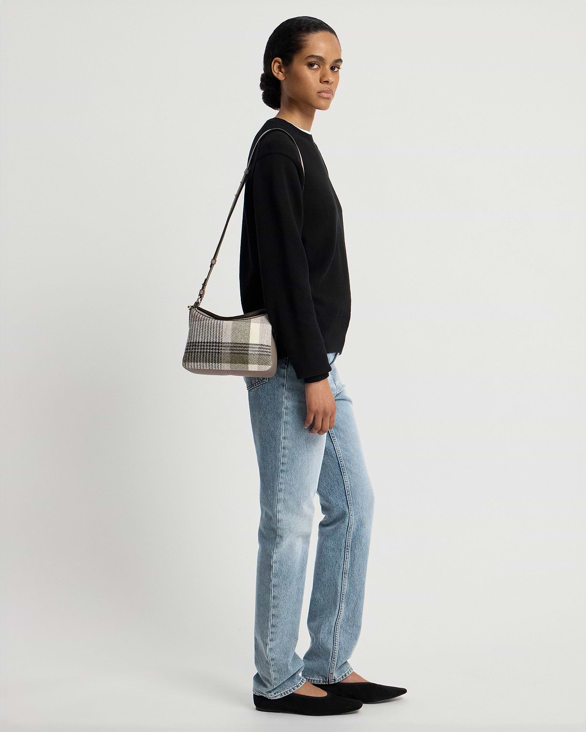 Model wearing checked tartan taupe shoulder bag with black jumper and jeans.