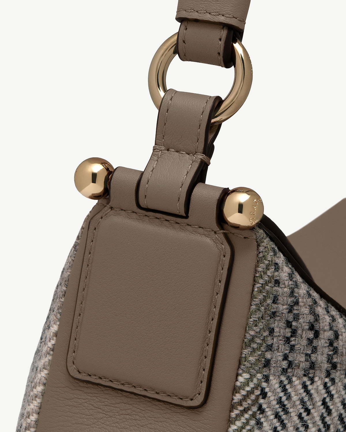 Detail of Strathberry Sway strap with taupe leather, tartan tweed and gold hardware.