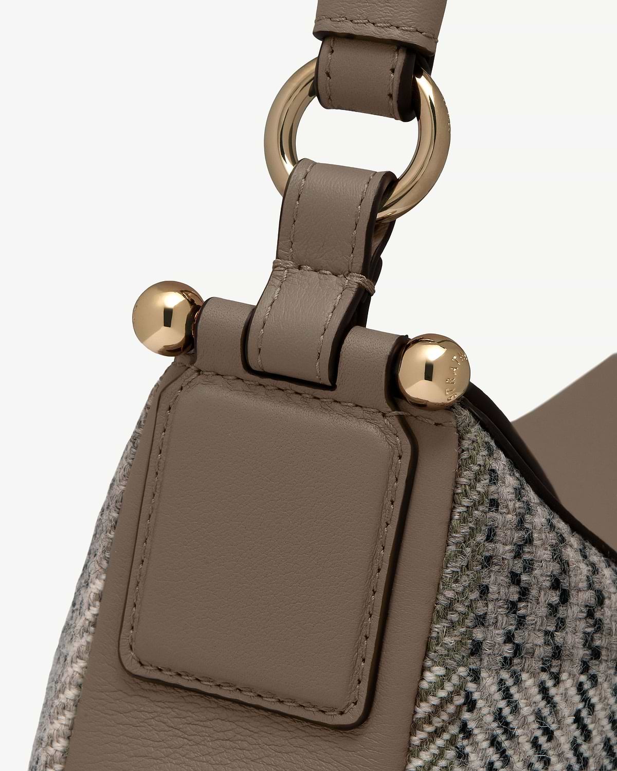 Detail of Strathberry Sway strap with taupe leather, tartan tweed and gold hardware.