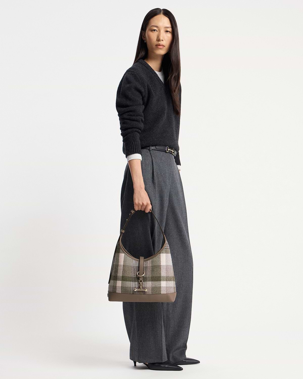 Model holding tartan taupe kite hobo bag with leather trim and gold hardware