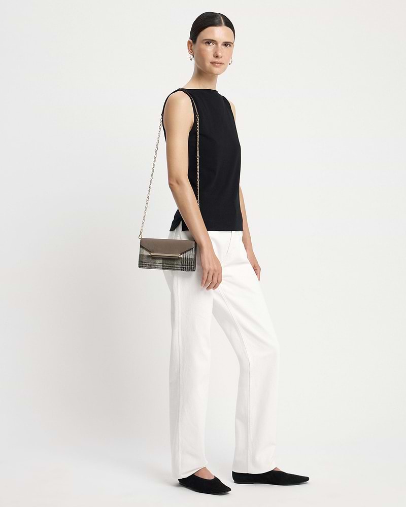 Model wearing a chain-strap tartan taupe wallet at her hip.