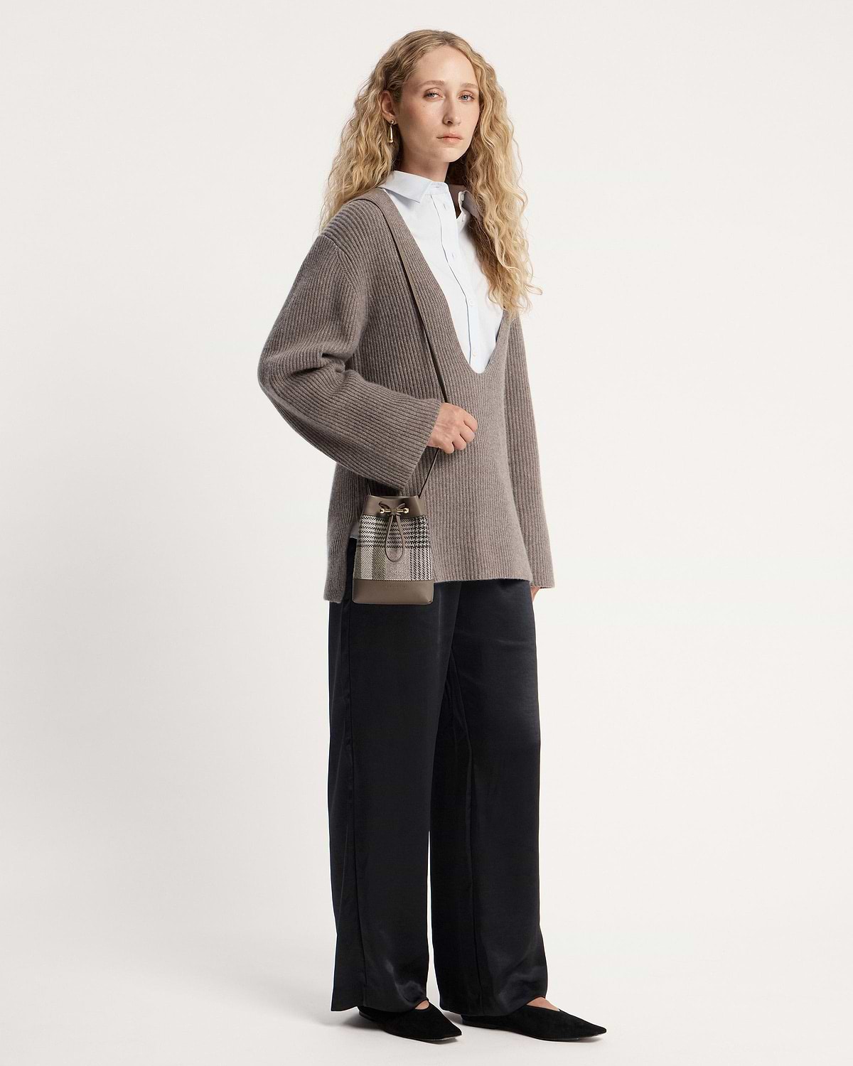 Woman wearing taupe ribbed jumper and tartan taupe midi pouch cross-body.