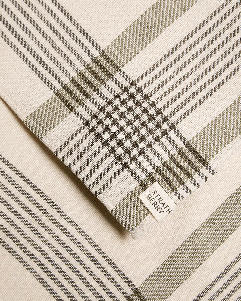 Folded Strathberry tartan cotton and linen table runner in cream and olive tones.