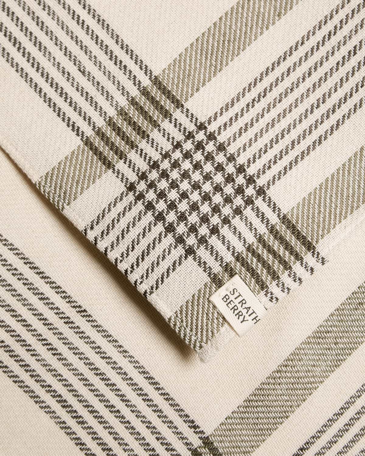 Folded Strathberry tartan cotton and linen table runner in cream and olive tones.