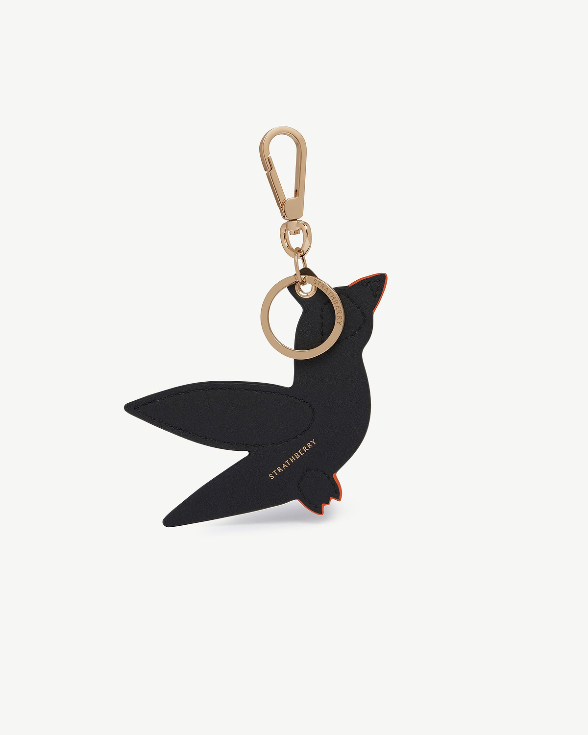 Black and orange leather bird bag charm with gold clasp and ring, Strathberry logo.