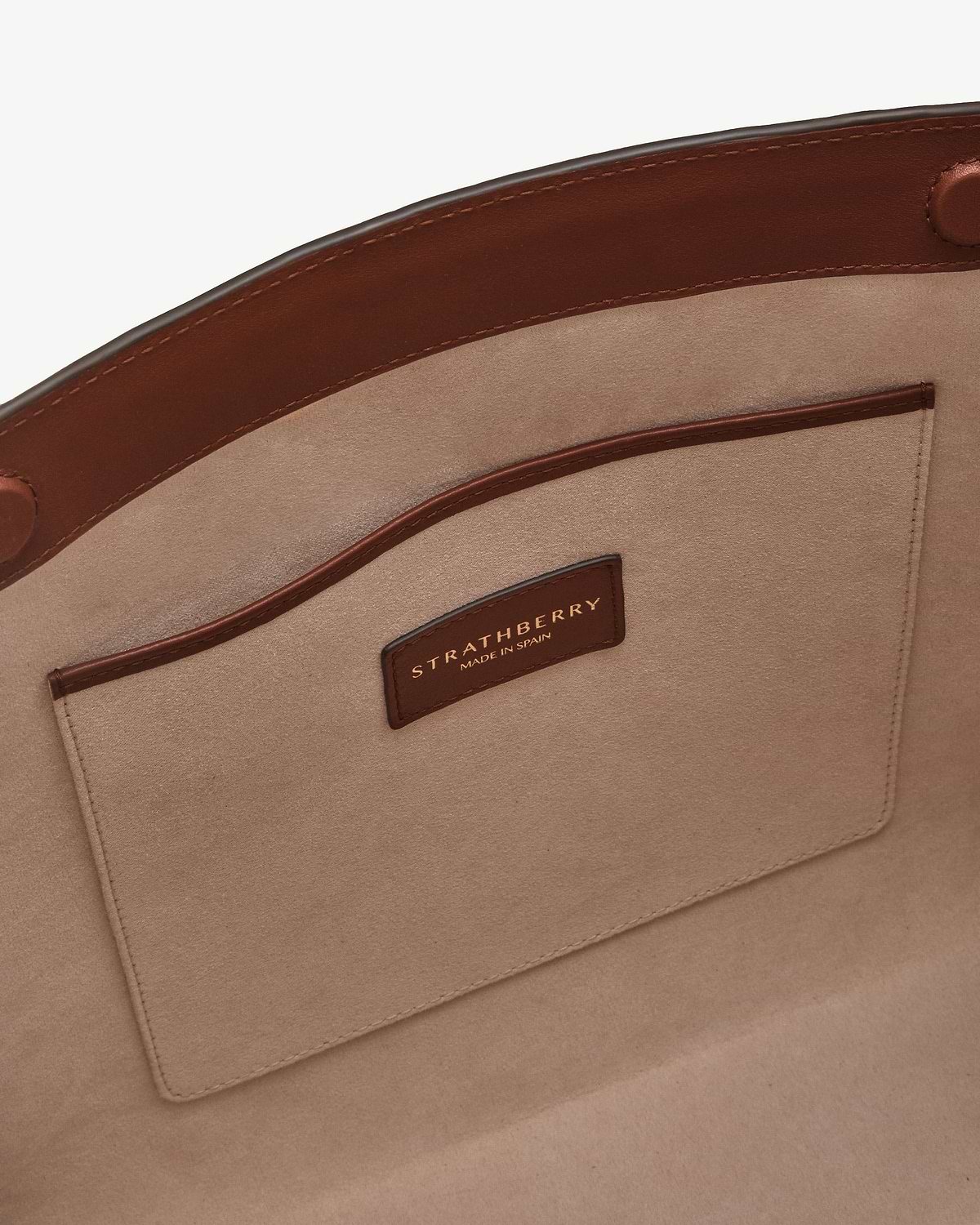 Walnut leather tote interior pocket and Strathberry label with gold lettering.