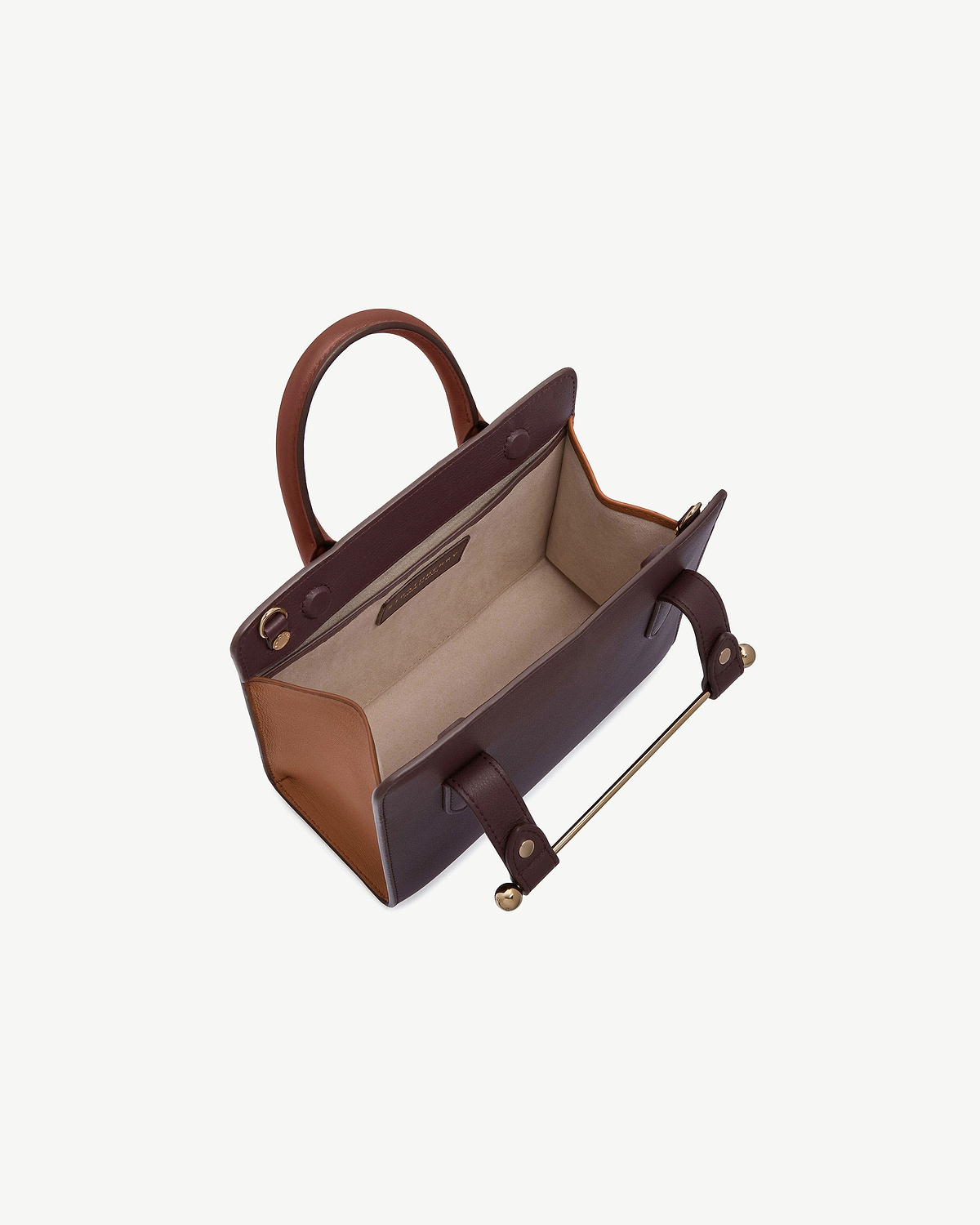 Mini tote with open interior, burgundy body, chestnut sides and walnut handles.