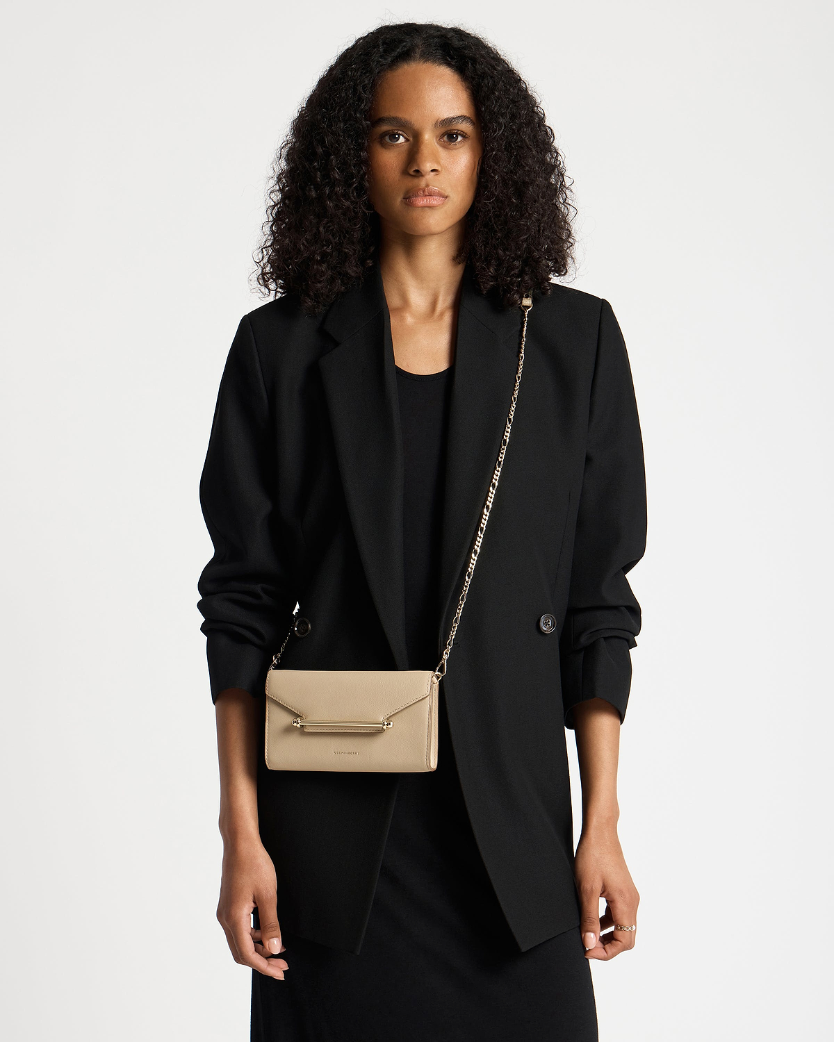 Model wearing black blazer with sand-coloured Multrees chain wallet on a gold chain.