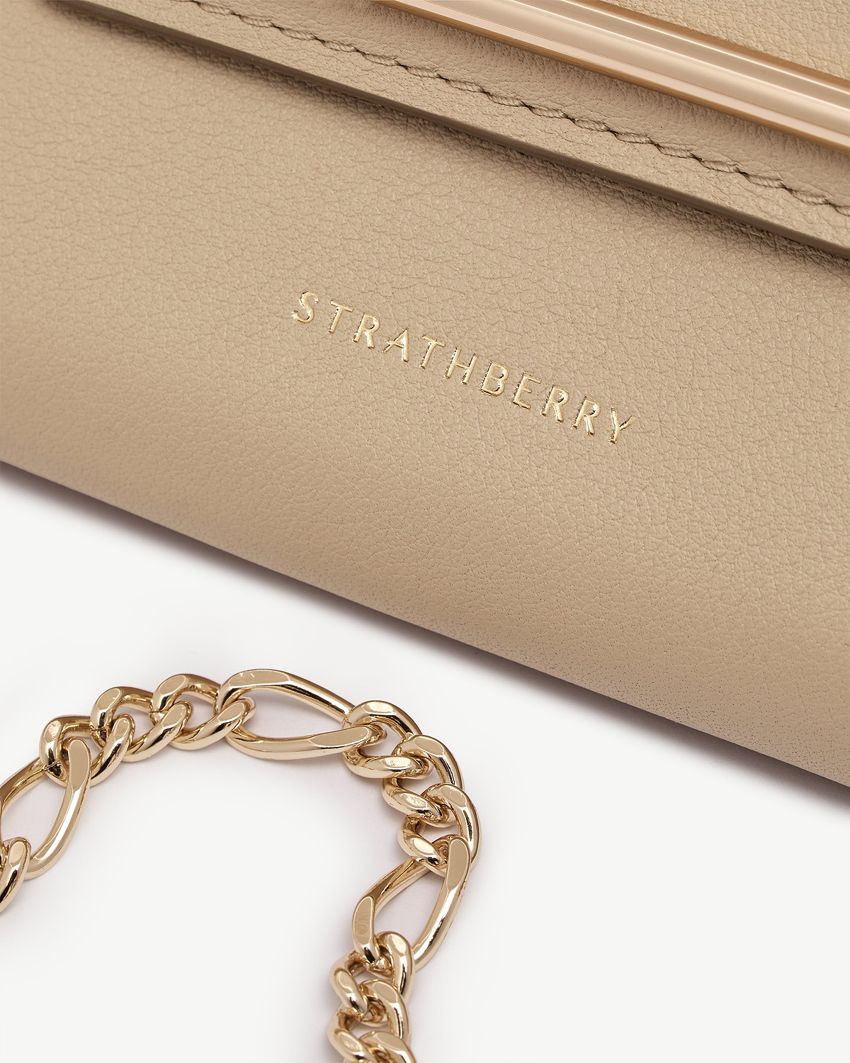 Sand leather Multrees chain wallet with gold chain and Strathberry logo visible.