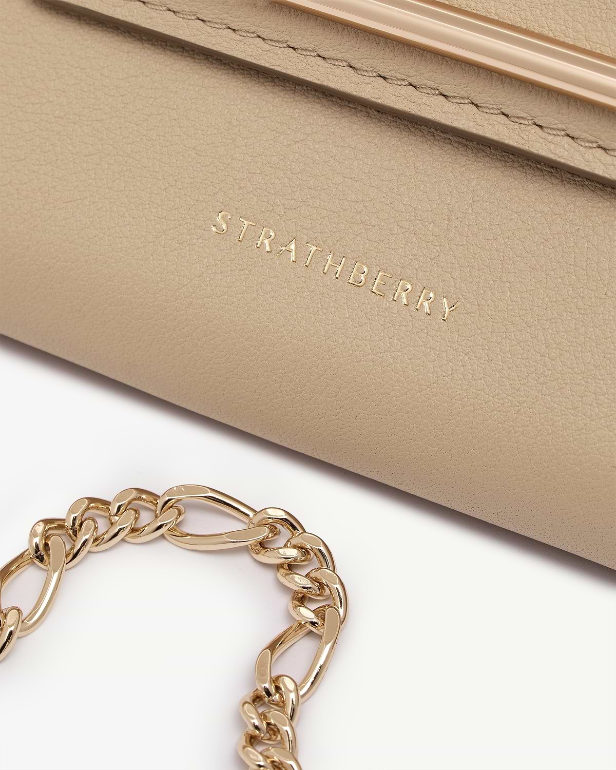 Sand leather Multrees chain wallet with gold chain and Strathberry logo visible.