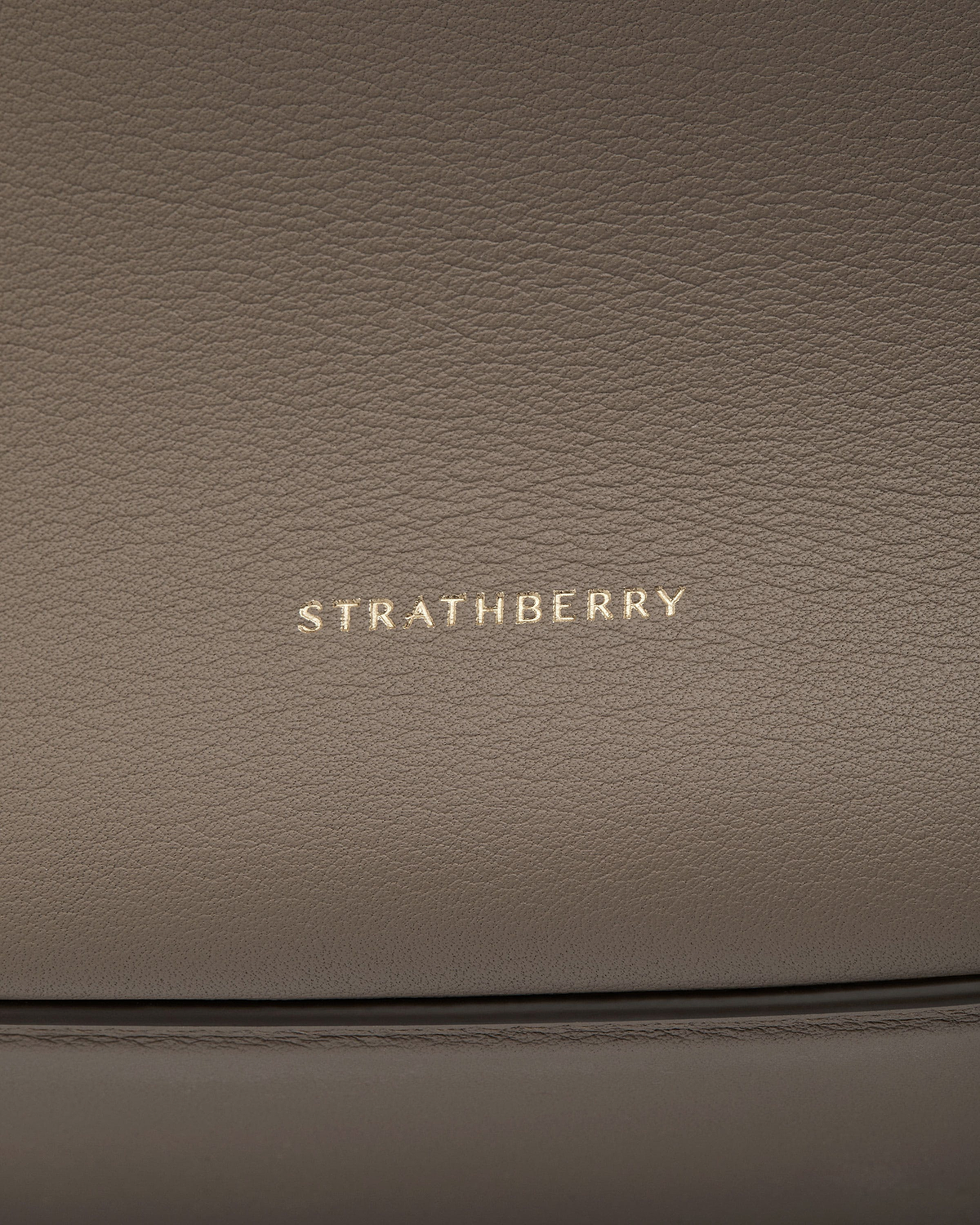 Taupe pebbled leather with gold Strathberry logo and stitched seam details.