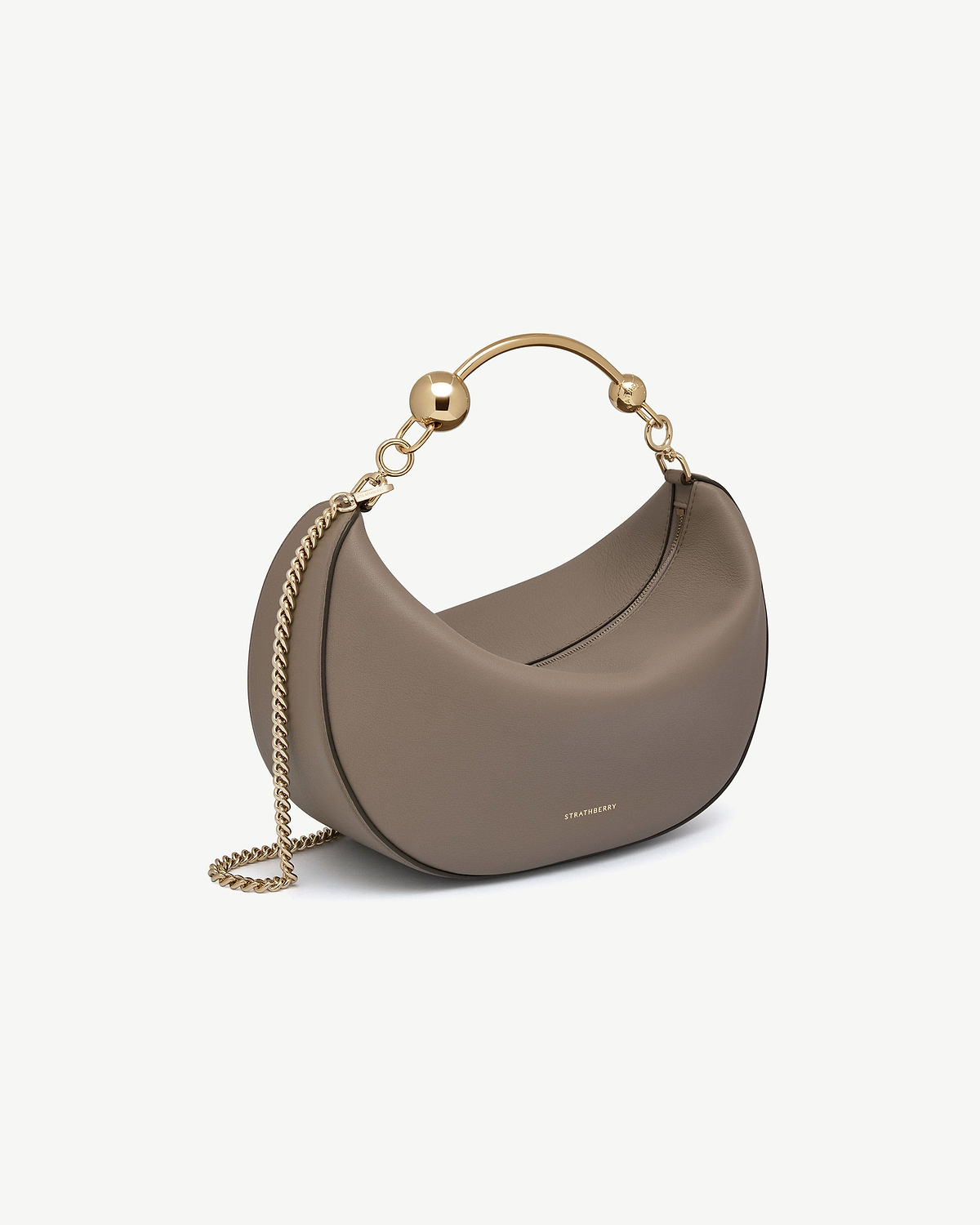 Taupe crescent-shaped leather bag with gold chain and Strathberry logo.
