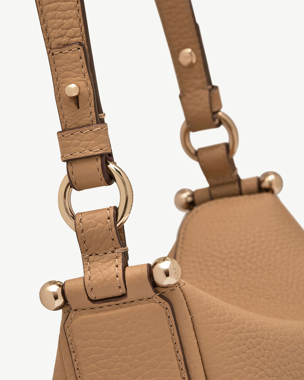 Caramel leather bag strap with gold rings and ball-stud hardware close-up