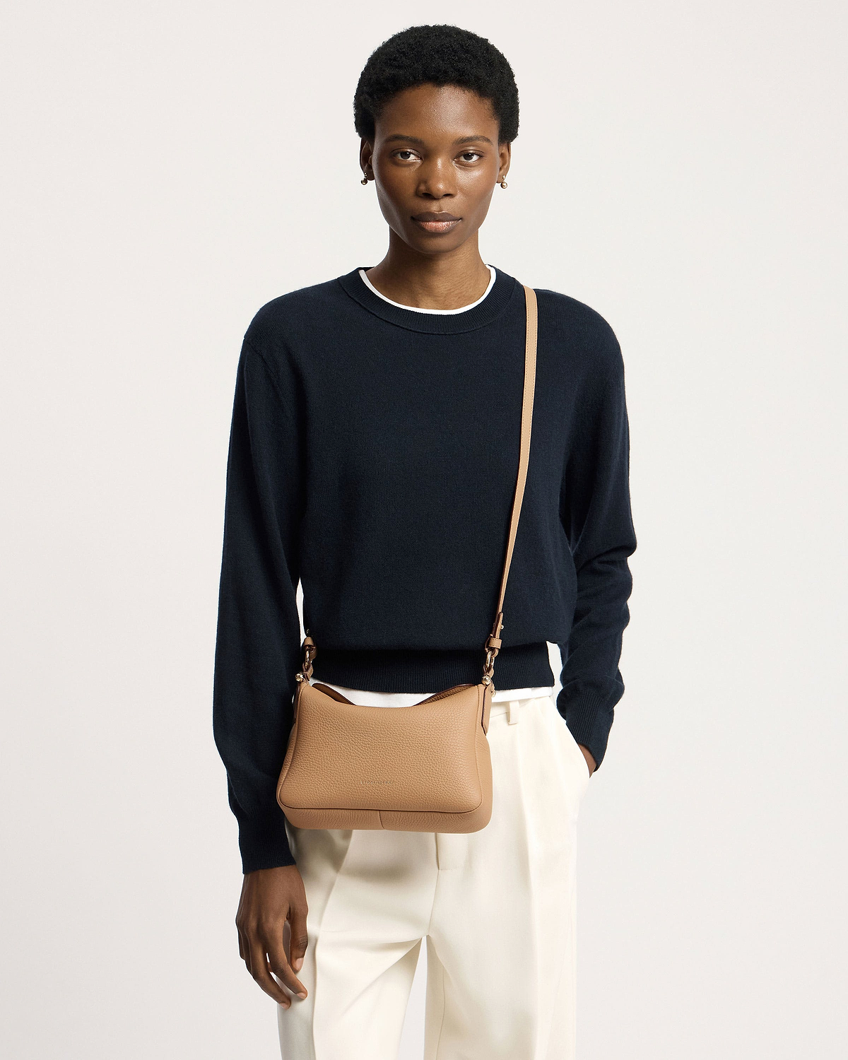 Model wearing a caramel Sway leather shoulder bag crossbody with navy jumper