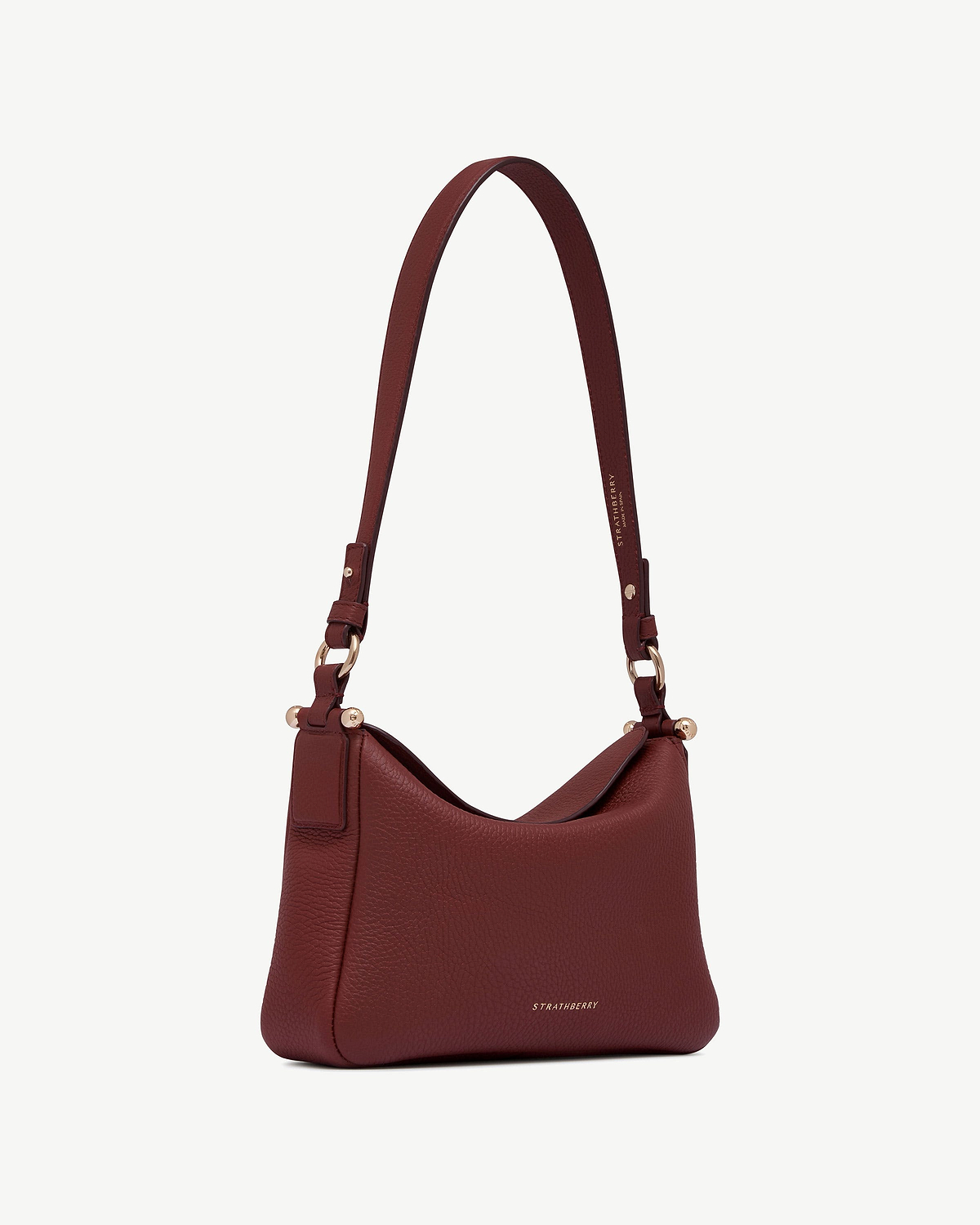 Strathberry Sway oxblood leather shoulder bag with adjustable strap and gold hardware.