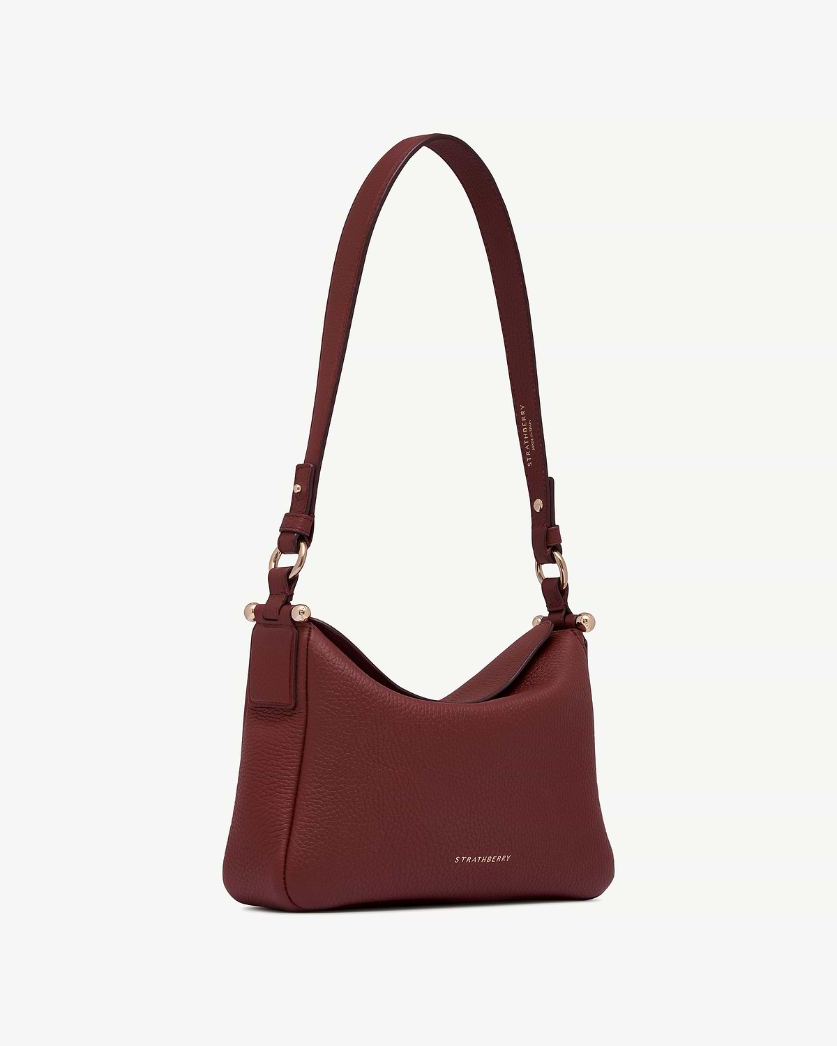 Strathberry Sway oxblood leather shoulder bag with adjustable strap and gold hardware.
