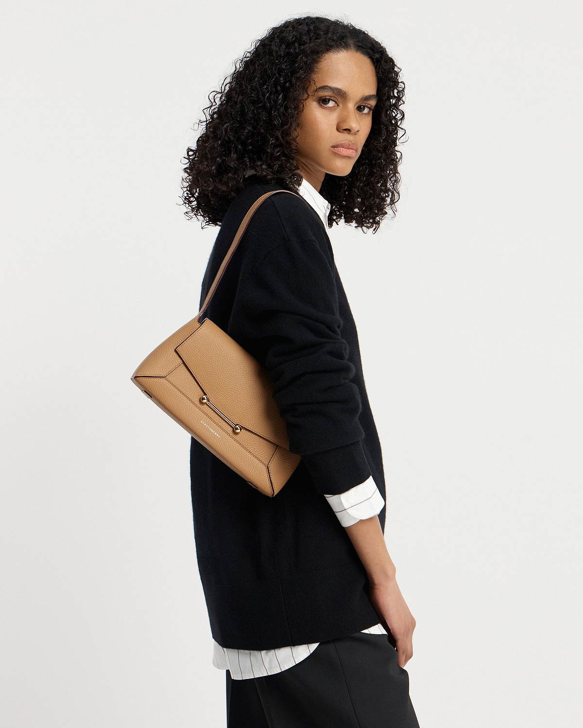 Woman wearing black jumper carrying caramel mosaic shoulder bag by Strathberry