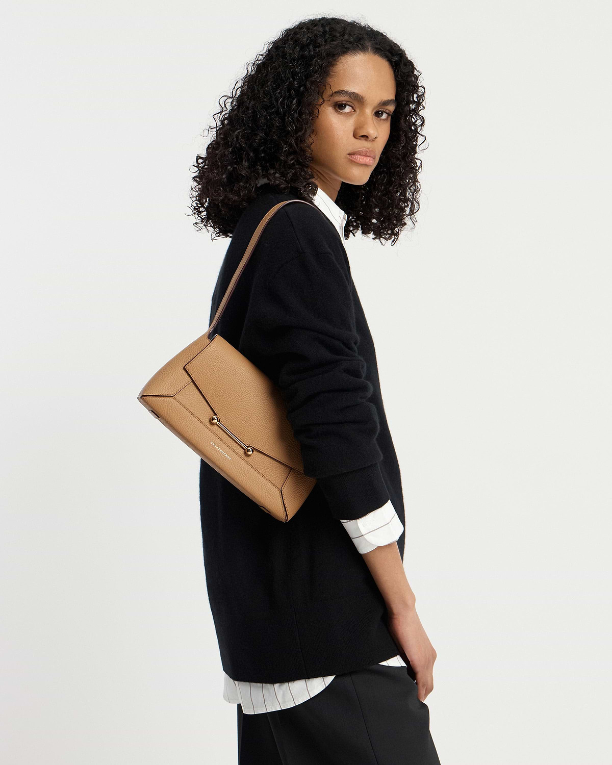 Woman wearing black jumper carrying caramel mosaic shoulder bag by Strathberry