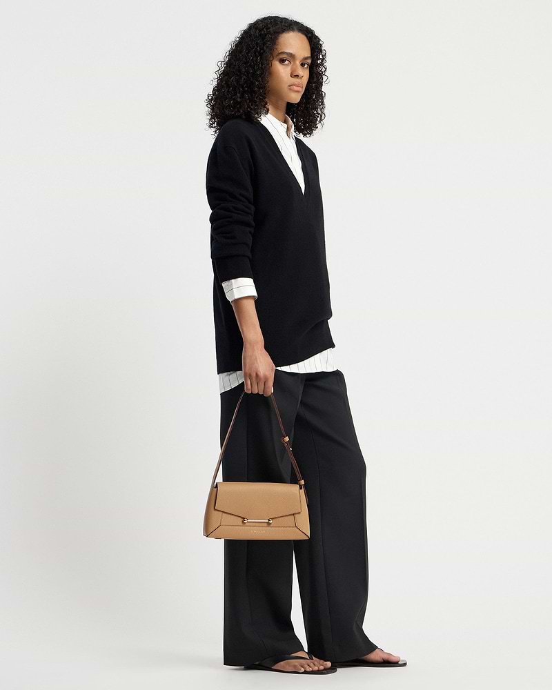 Model holding caramel mosaic shoulder bag with top handle and long strap.