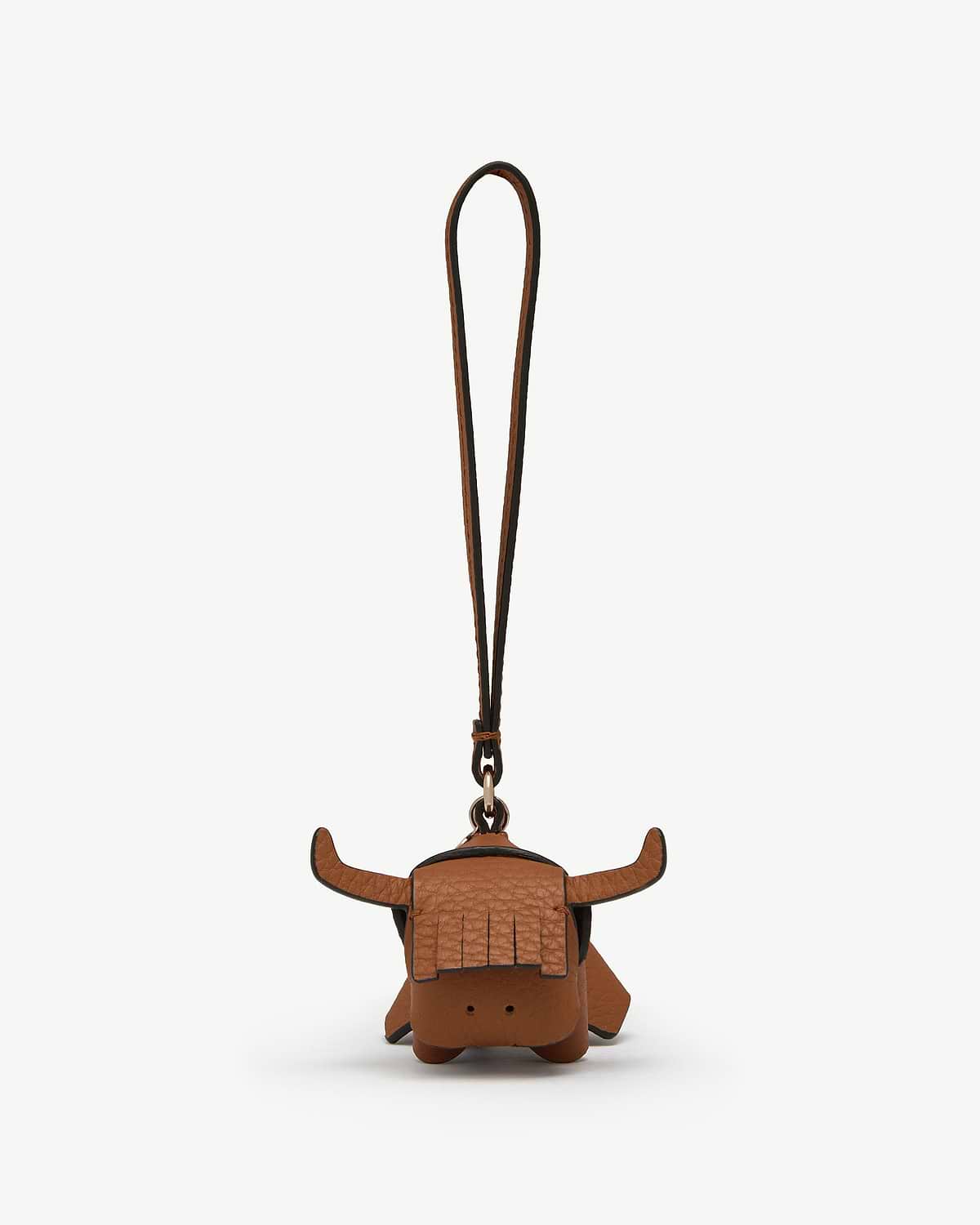 Tan leather highland cow bag charm with fringe, horns and long hanging strap.