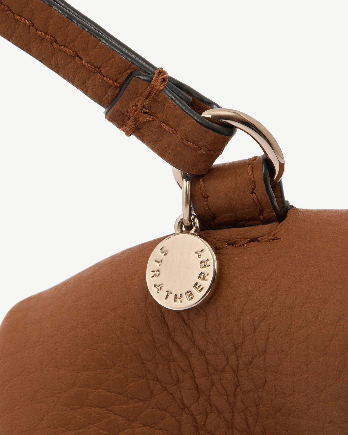 Highland cow tan leather bag charm with round Strathberry stamped disc.
