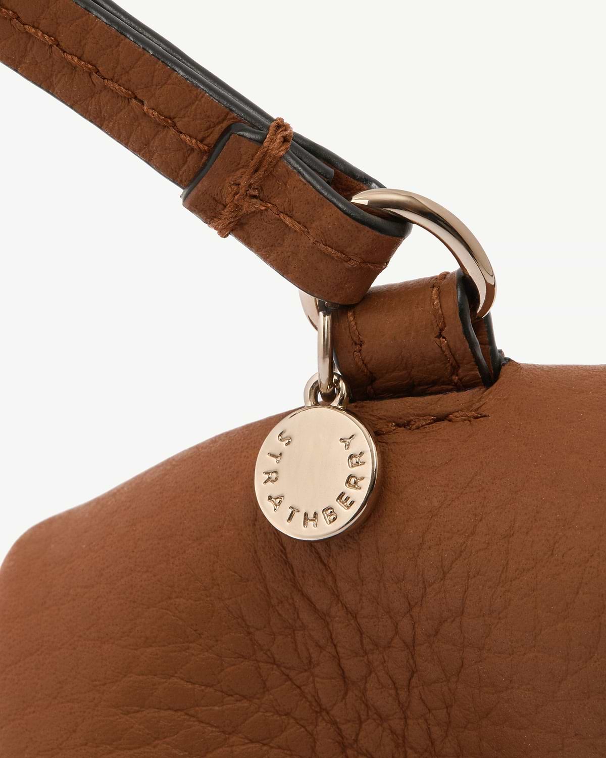 Highland cow tan leather bag charm with round Strathberry stamped disc.