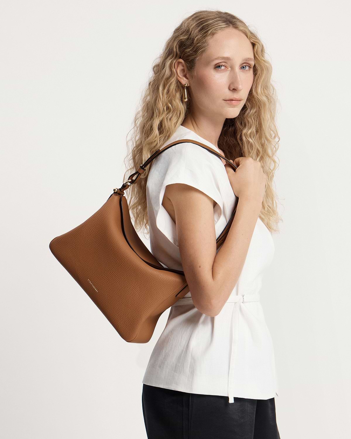 Model wearing a tan Strathberry Sway Maxi shoulder bag over her shoulder