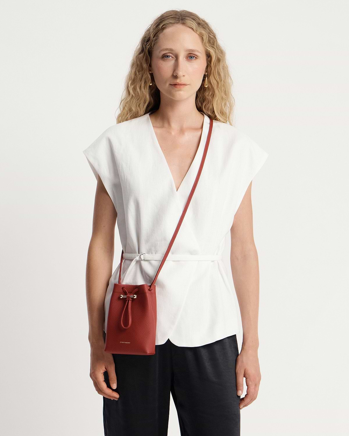 Woman in white top wearing Levanto red Osette Midi Pouch crossbody
