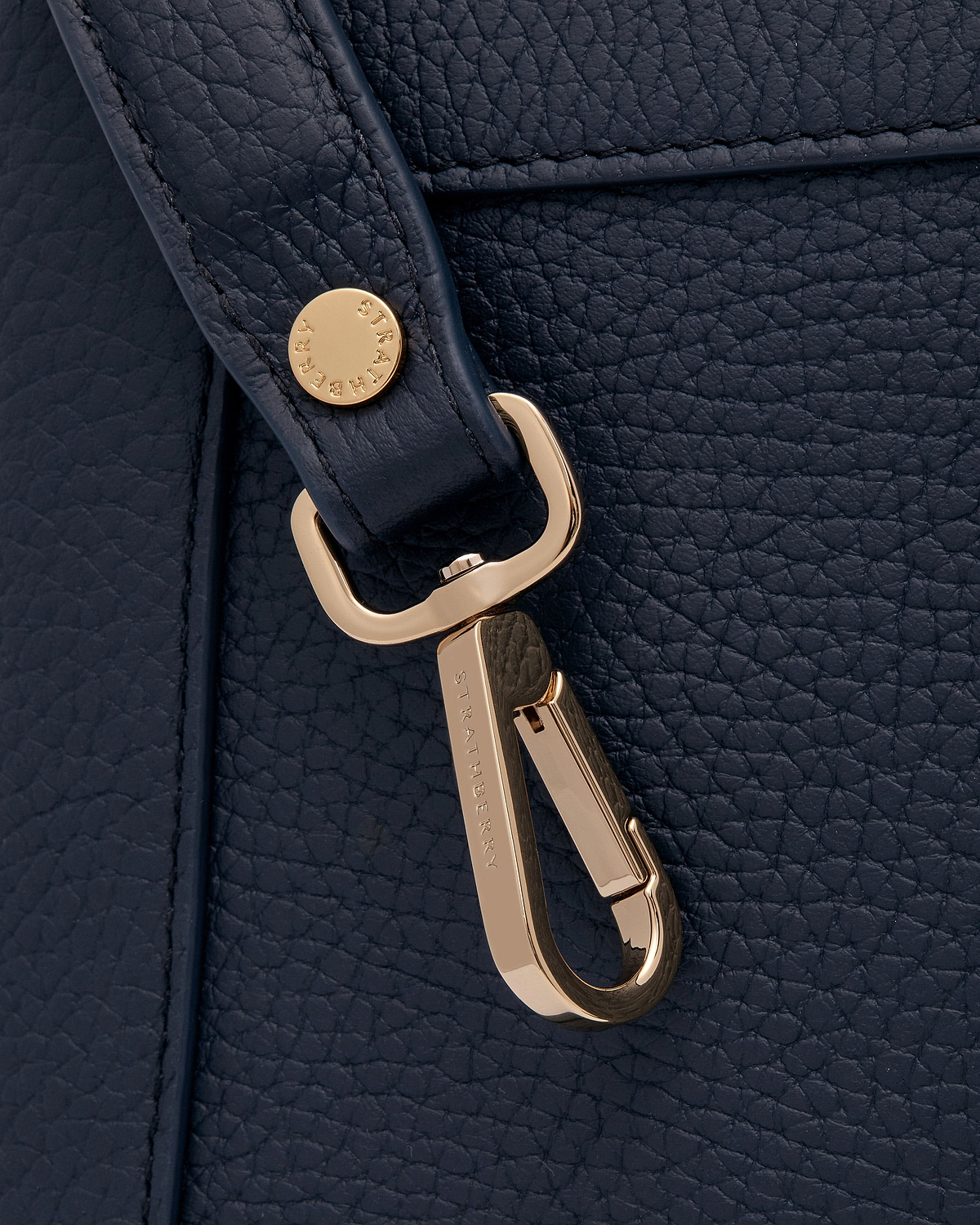 Navy pebbled leather bag strap with gold Strathberry clasp detail.