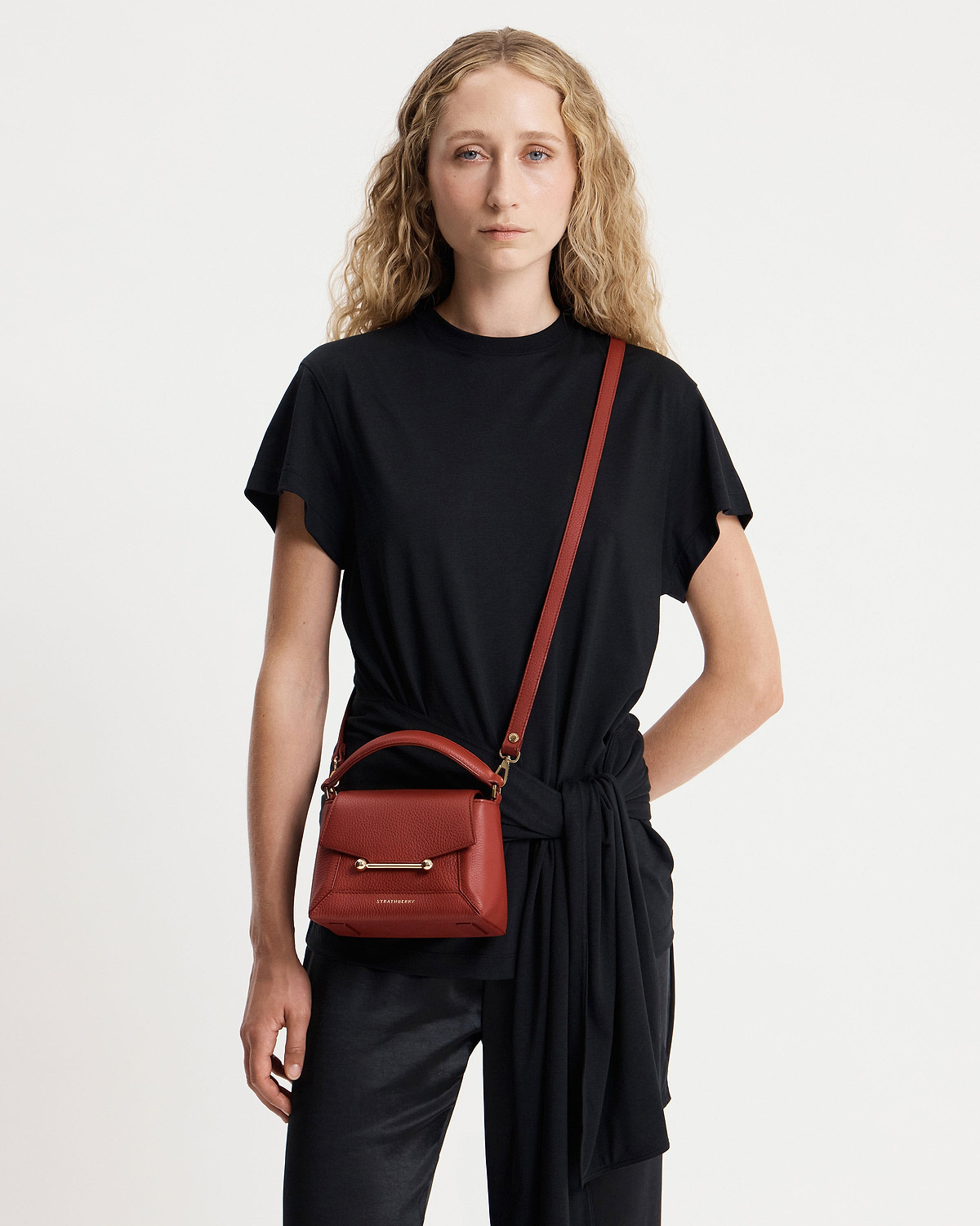 Model wearing black top with Strathberry Mosaic Nano Levanto Red crossbody bag.