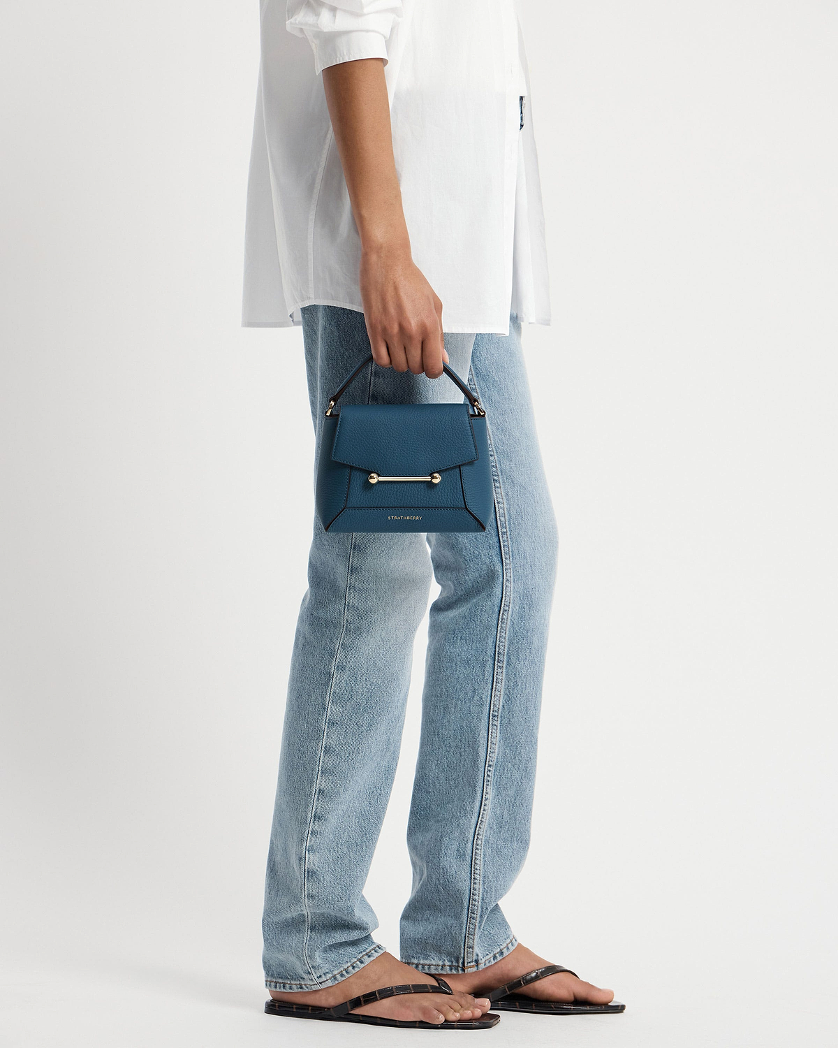 Strathberry Mosaic Nano loch blue top-handle bag held by model.