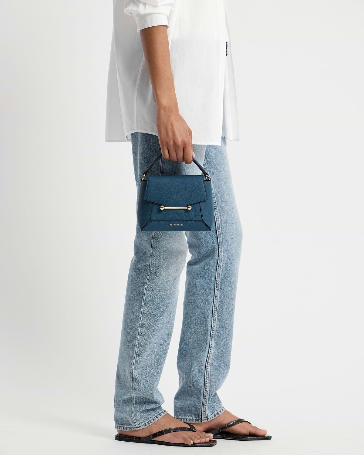 Strathberry Mosaic Nano loch blue top-handle bag held by model.
