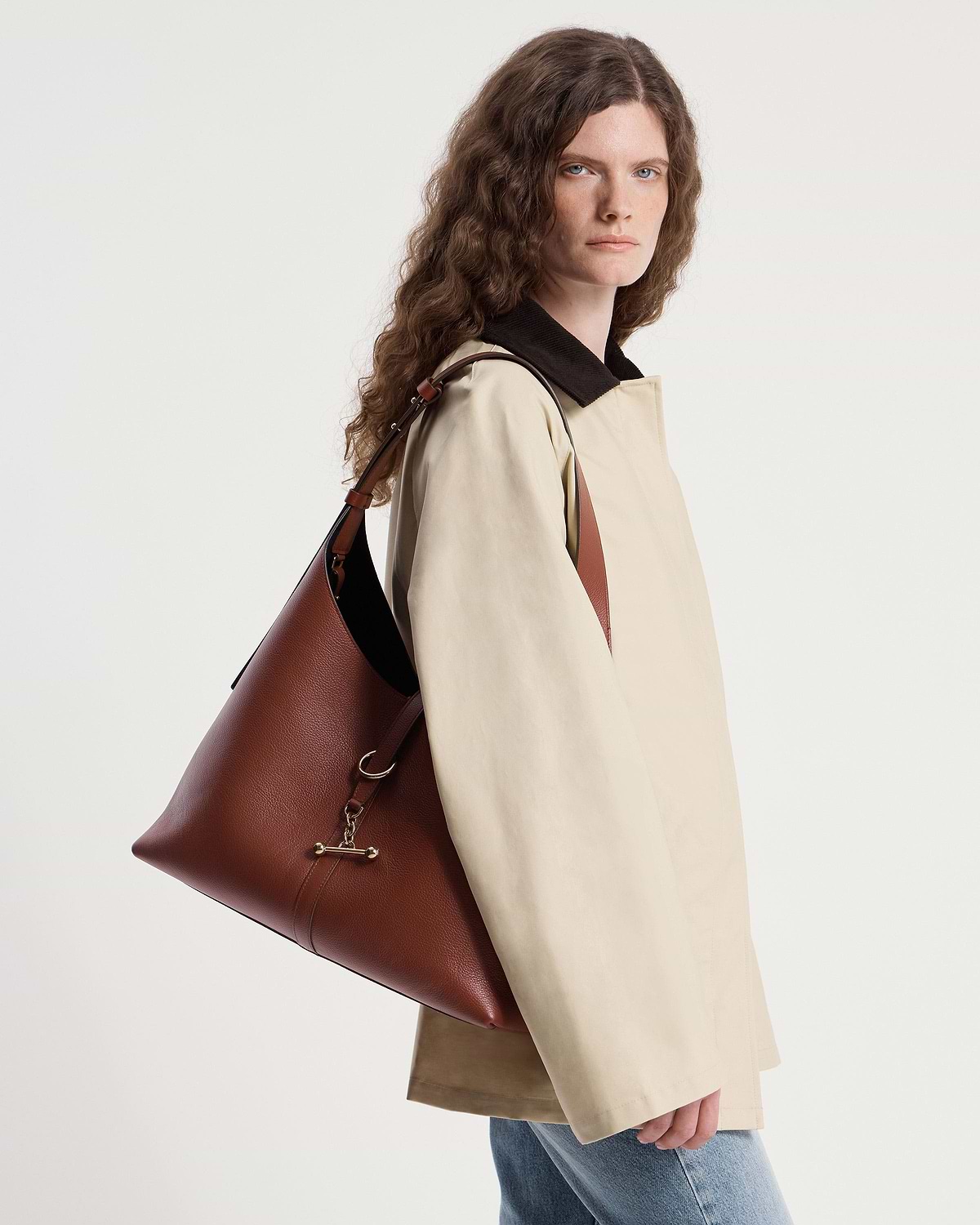 Woman in beige coat carrying a walnut leather Kite Hobo Maxi bag over her shoulder.