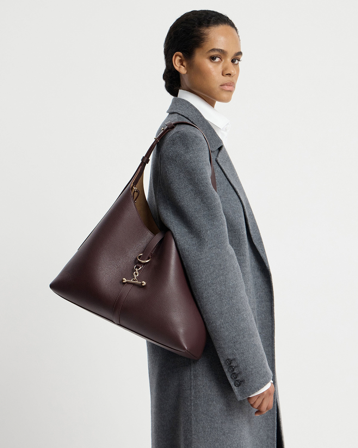 Model wearing a burgundy hobo shoulder bag over a grey coat.