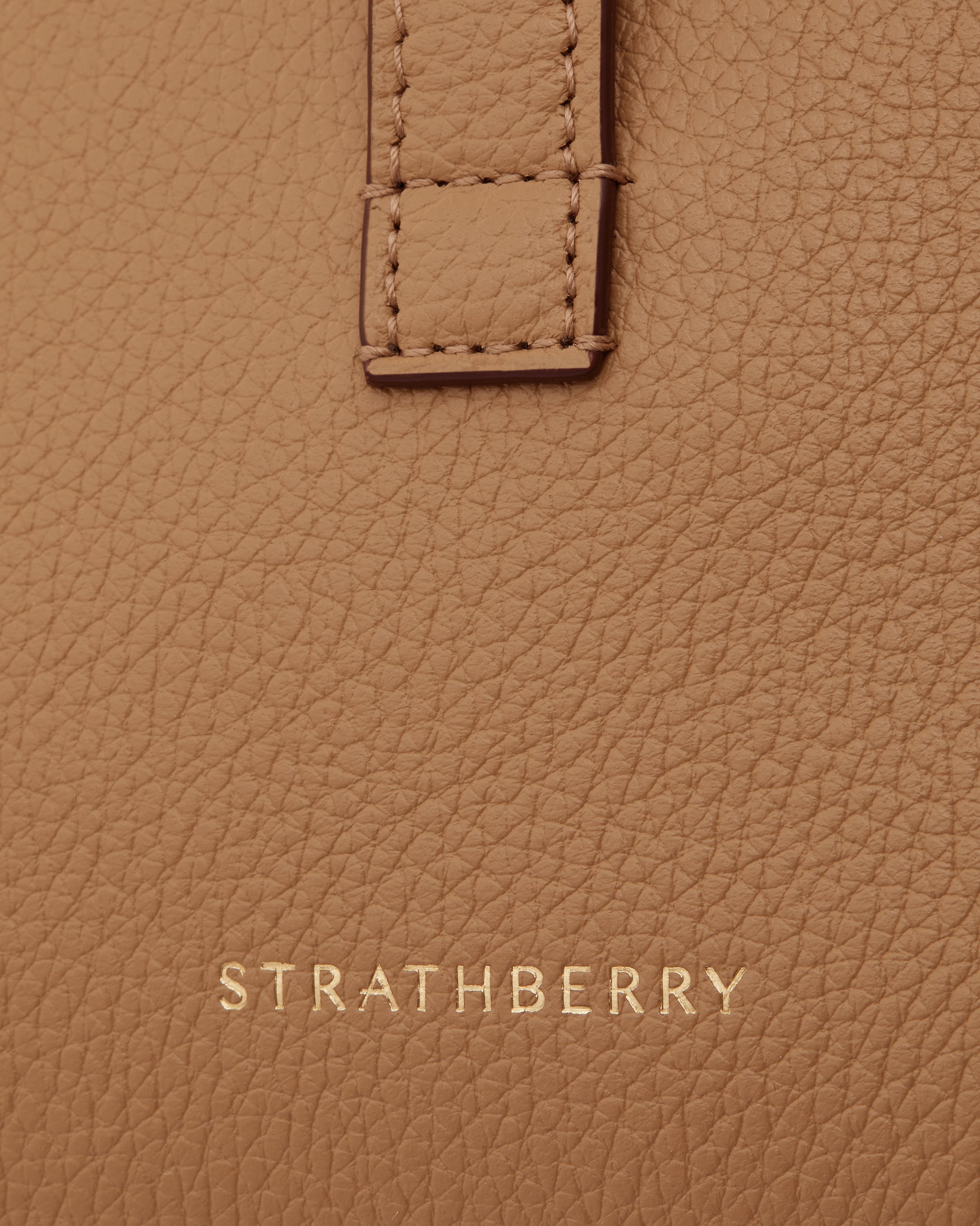 Caramel pebbled leather with stitched strap detail and gold Strathberry logo.