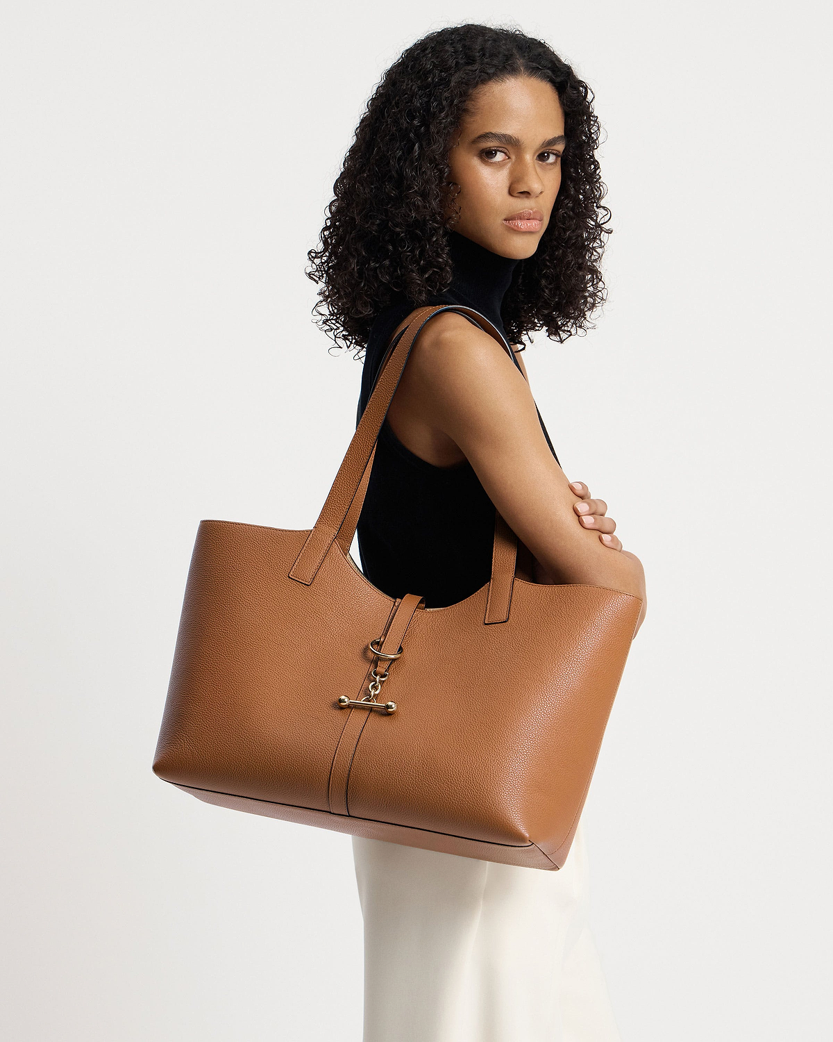 Model in a black sleeveless top carrying a tan tote bag over her shoulder