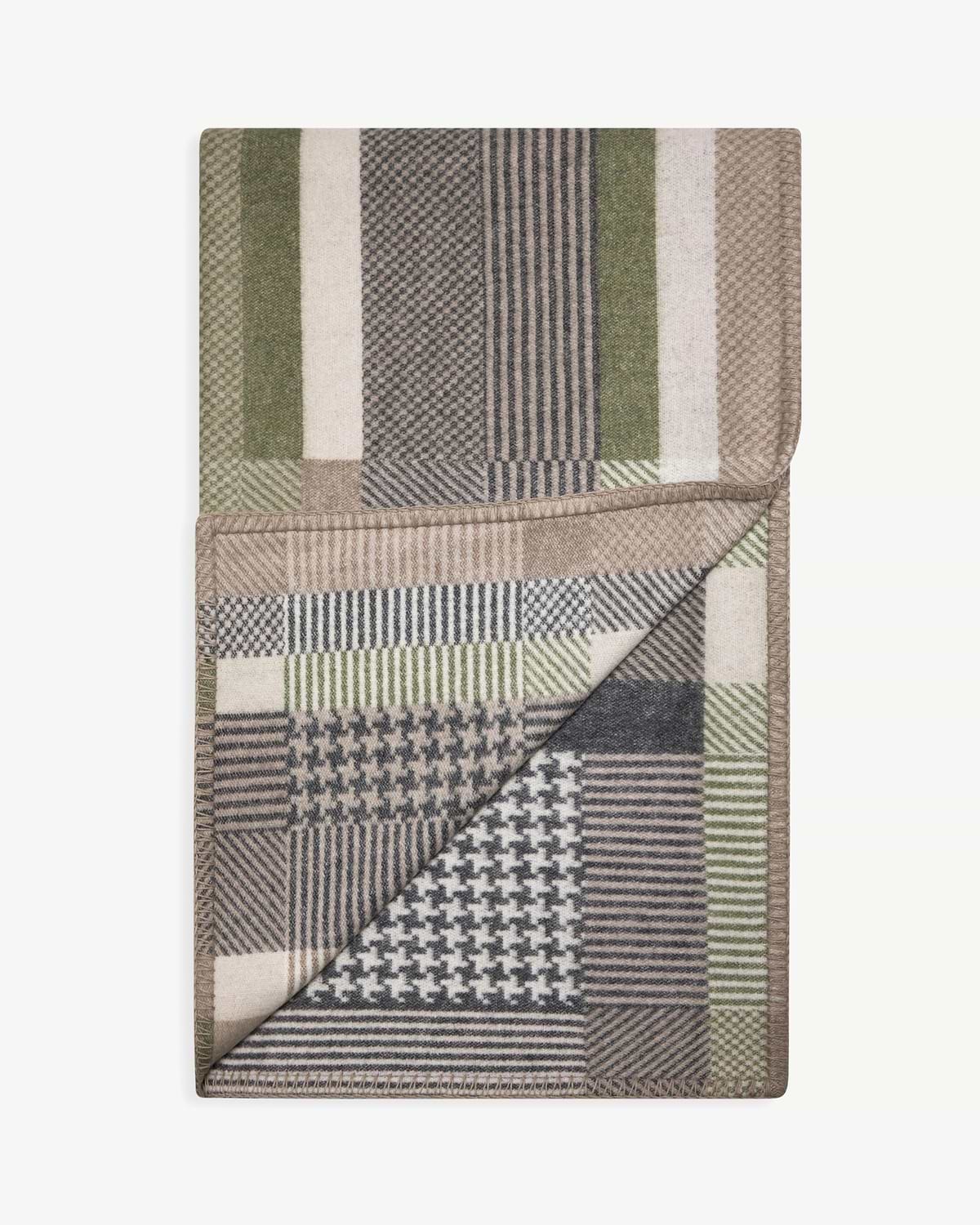 Folded tartan blanket with green, grey and beige checks and houndstooth pattern.