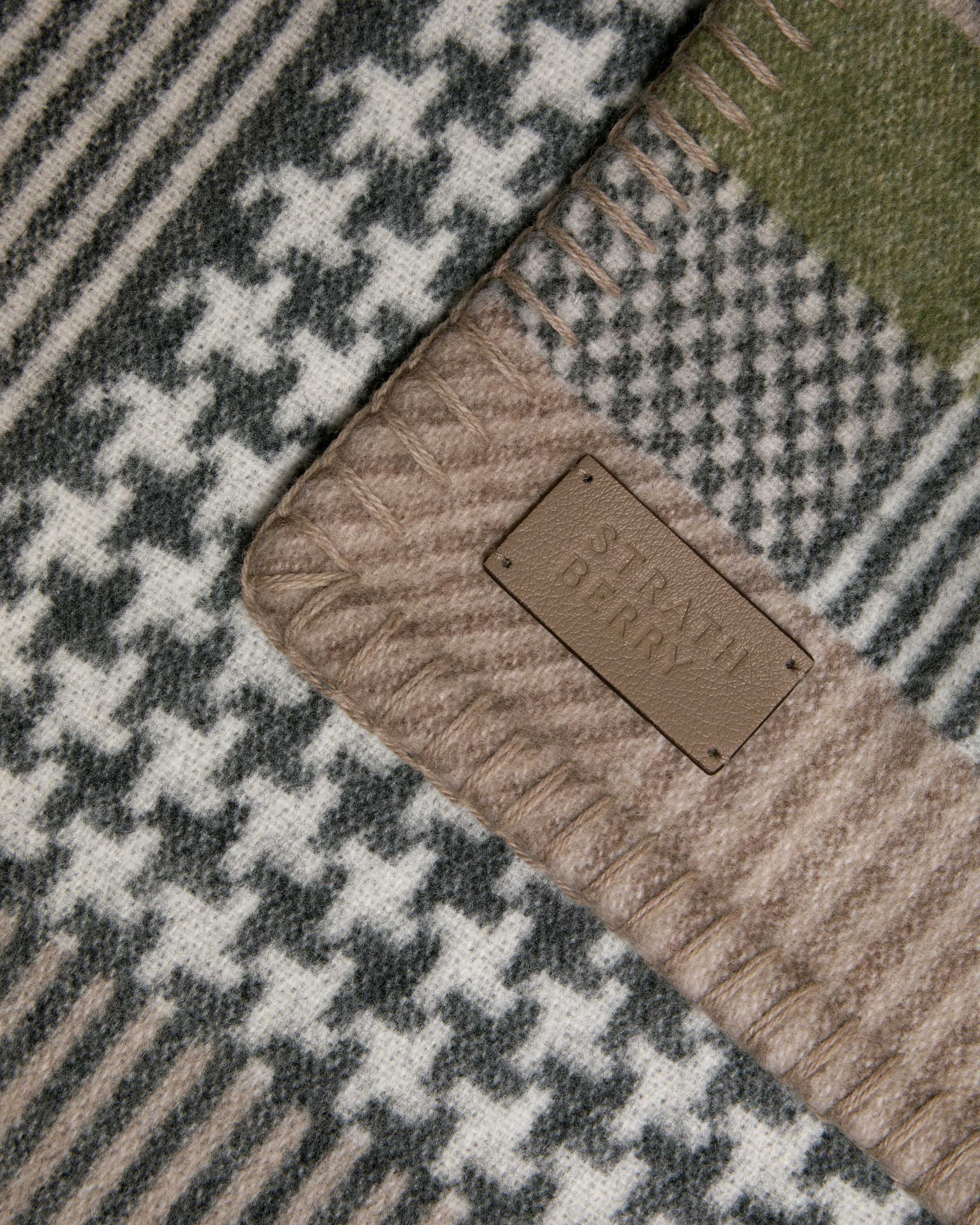 Strathberry tartan wool and cashmere blanket showing fringe and leather label.
